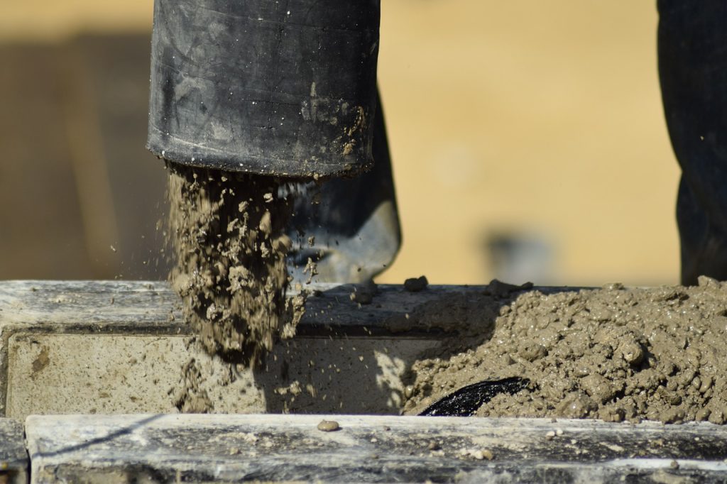 Concrete pumping with heavy machinery breaking and removing old concrete.